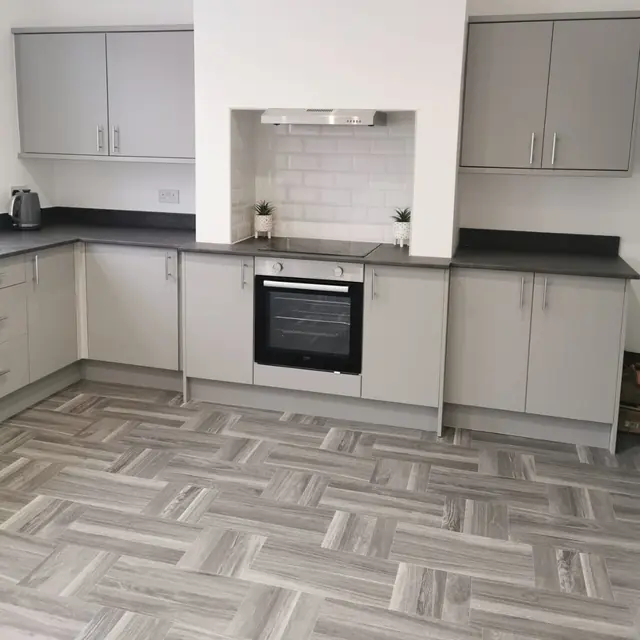 Newly fitted kitchen with grey units and herringbone flooring